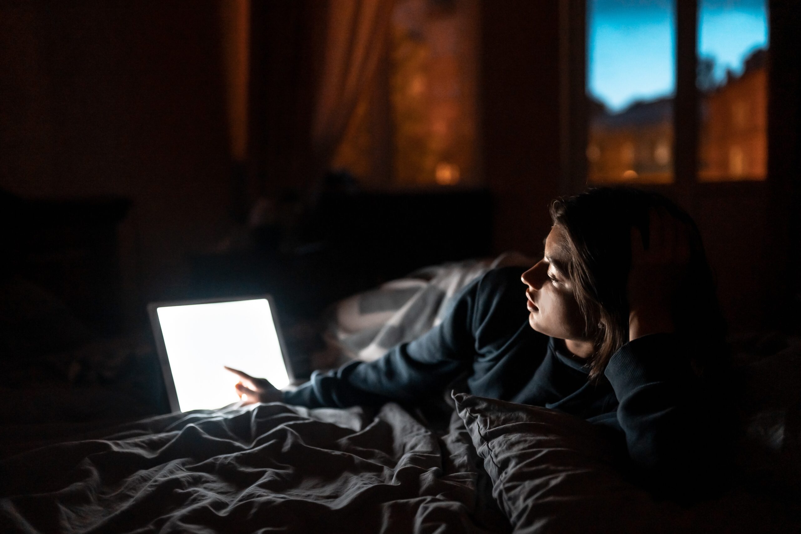a person looking at a laptop while laying in bed